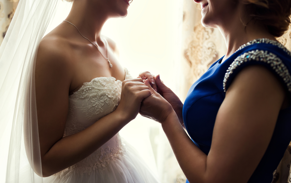 Bride on wedding day holding her mother's hands. Concept of relationship between moms and daughters.