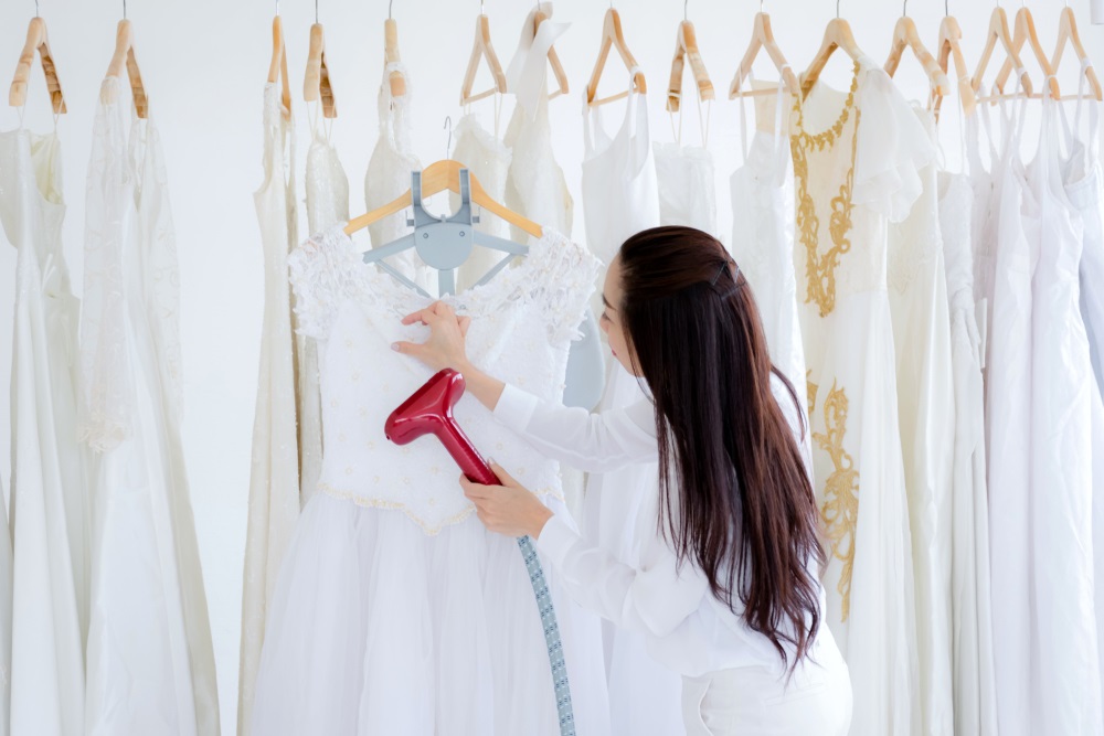 Women Ironing wedding dress in studio by Ironing machine. Wedding concept.