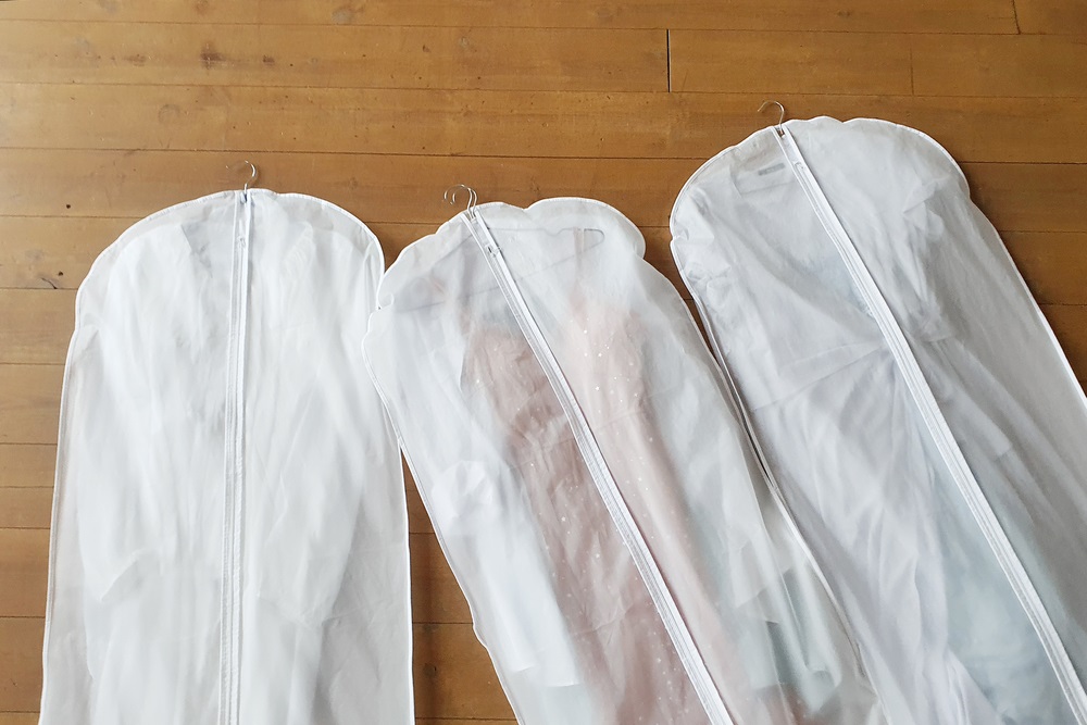  Three white Hanging Garment Bag on the floor. The morning before the wedding. Pack your things on a trip or sort and hang up your wardrobe.