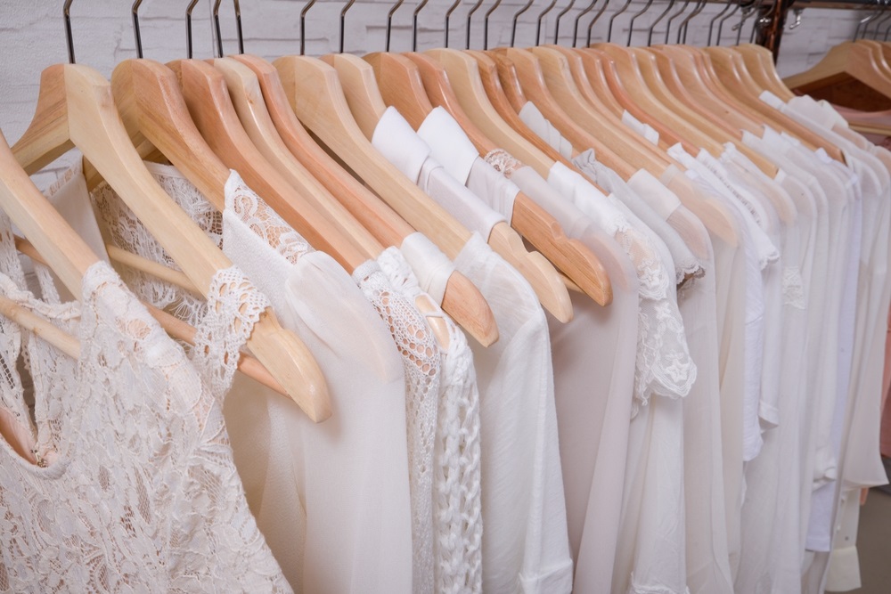 female different white clothes ,dress, shirt on hangers in store.